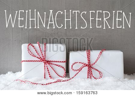 German Text Weihnachtsferien Means Christmas Holidays. Two White Christmas Gifts Or Presents On Snow. Cement Wall As Background. Modern And Urban Style.