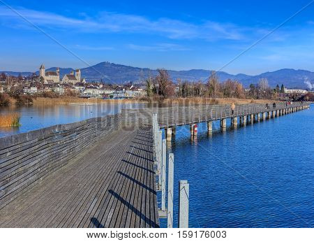 Rapperswil, Switzerland - 30 November, 2016: wooden pedestrian bridge over Lake Zurich between the town of Rapperswil and the village of Hurden - the longest wooden bridge in Switzerland.