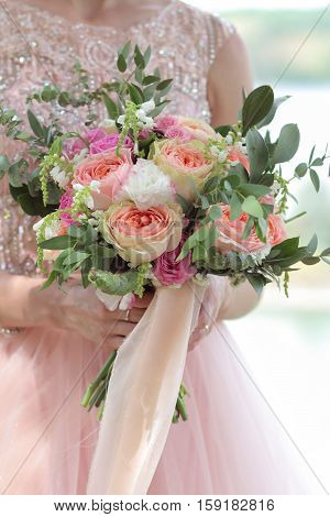 Bride holding a beautiful bridal bouquet. Wedding bouquet of peach roses by David Austin single-head pink rose aqua eucalyptus ruscus gypsophila
