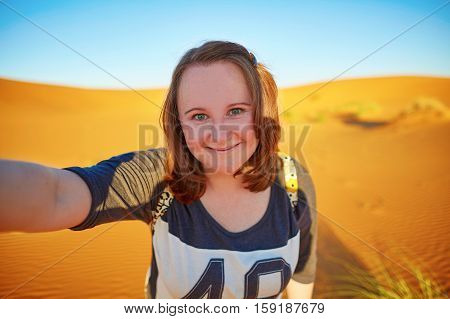 Happy smiling tourist taking selfie with sand dunes in Sahara desert at Erg Chebby Merzouga Morocco
