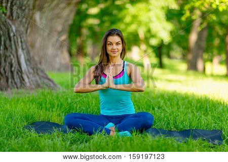 Yoga woman on green grass girl relaxing in a field. Yoga woman on green park girl doing gymnastics outdoors. Meditating woman in meditation in yoga pose practicing outdoors.