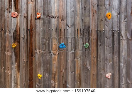 Grunge surface of old wood climbing wall with toe and hand hold studs.