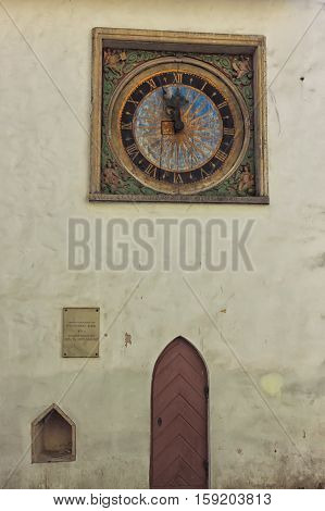 An old clock and a wooden door on the wall of the Church of the Holy Spirit in the old town of Tallinn Estonia.
