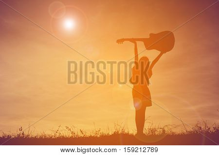 Silhouette happy girl playing guitar at the sky sunset happy time in holiday vintage tone