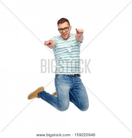 happiness, freedom, motion and people concept - happy young man jumping in air and pointing fingers to you