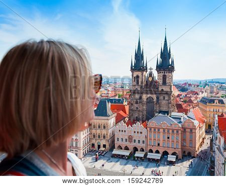Kostel Panny Marie pred Tynem. Church of the Virgin Mary. A young woman stands on top of the clock tower and looks at the Old Town Square in Prague