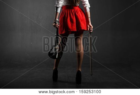 Female feet. A woman in a red skirt with a violin and fiddlestick