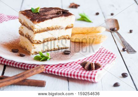 Traditional italian sweet tiramisù cake on White plate with cookies and coffee beans
