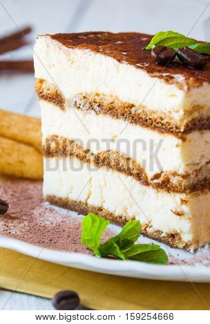 Traditional italian sweet tiramisù cake on White plate with cookies and coffee beans