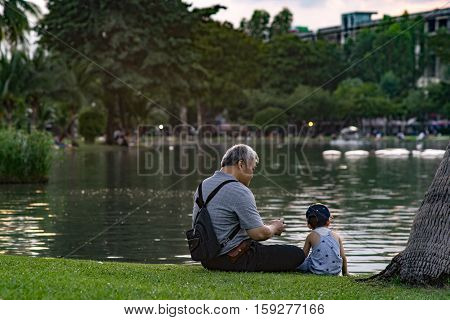 CHATUCHAK PARK, BANGKOK, THAILAND - NOVEMBER 27 : Grandpa and grandson relaxing in Chatuchak Park on the November 27, 2016 in Chatuchak Park, Bangkok.