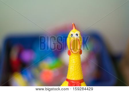 Toy Rubber Shriek Yellow Chicken On Blur Toy Background In Messy Room.