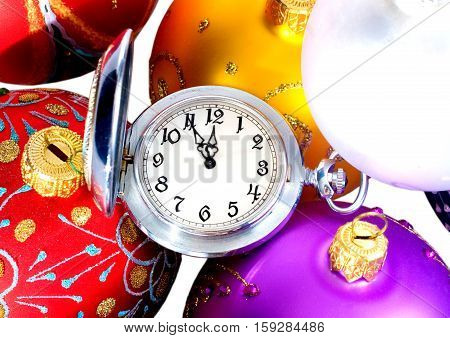 Pocket watch showing almost twelve o'clock (five minutes to the midnight) and multicolored Christmas balls New Year concept