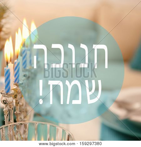 Menorah with candles on table served for Hanukkah celebration. Text HAPPY HANUKKAH in Hebrew