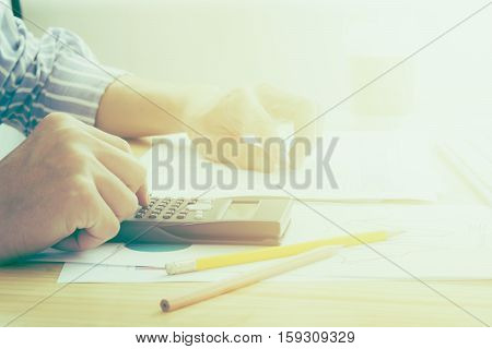 Close up of Business man working  calculating on financial report at the office with  calculator  retro tone