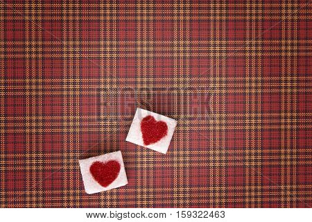 Sugar cubes with a red heart on one of them as background. Top view. Diet unhealty sweet addiction concept