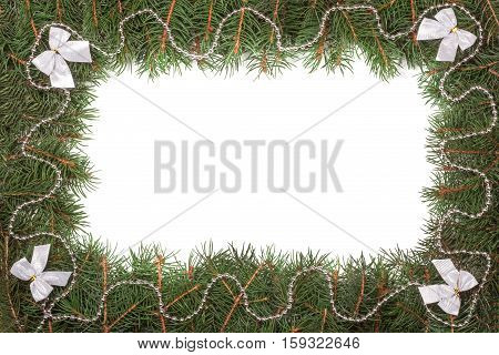 Christmas frame made of fir branches decorated with beads and bows isolated on white background.