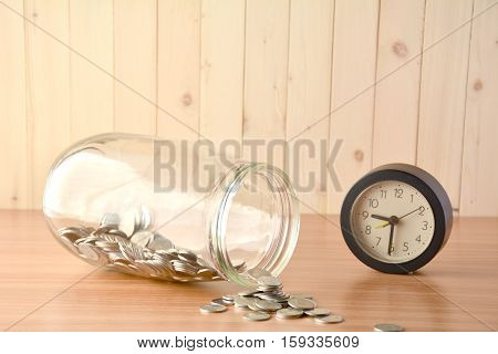 Coin spilled from a big bottle and alarm clock.