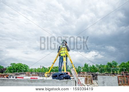 Surveyor engineer is measuring level on construction site. Surveyors ensure precise measurements before undertaking large construction projects.