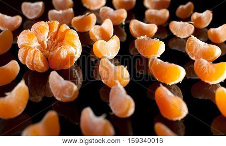 Group Of Mandarin Slices With Reflection On Black Background