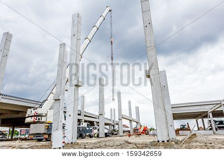 Mobile crane is operating to assembly concrete joist on new edifice.