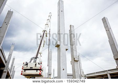 Mobile crane is operating to assembly concrete joist on new edifice.