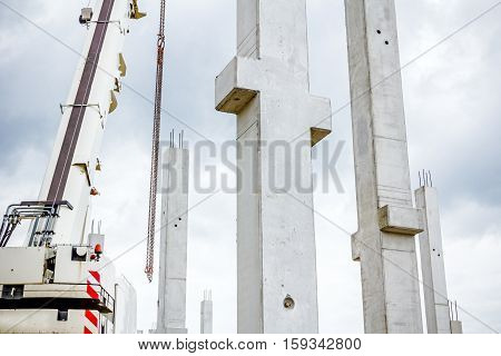 Mobile crane is operating to assembly concrete joist on new edifice.