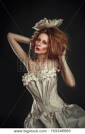 Beautiful redhead girl in elegant paper dress. Sensual image with bright makeup. Beauty model