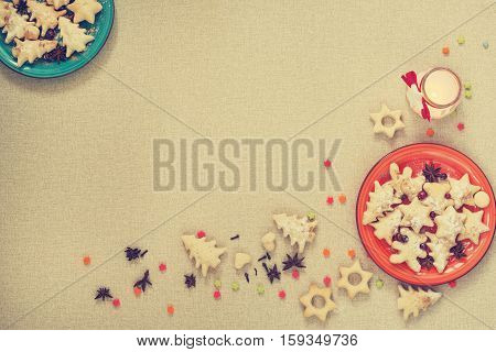 Cookies for Christmas is on the two plates in the corners on a light background standing next to the candle and scattered spices and other pastries. Copy space.