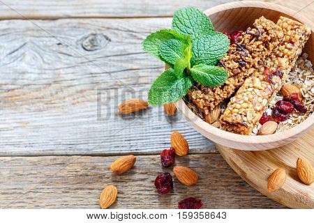 Wooden Bowl With Bars Of Cereal, Nuts, Dried Fruit And Mint.
