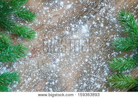Green Christmas Tree Branches On Winter Snowflakes Wooden Space Background