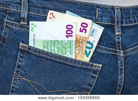 Euro banknotes sticking out of the blue jeans pocket. Money for travel and shopping