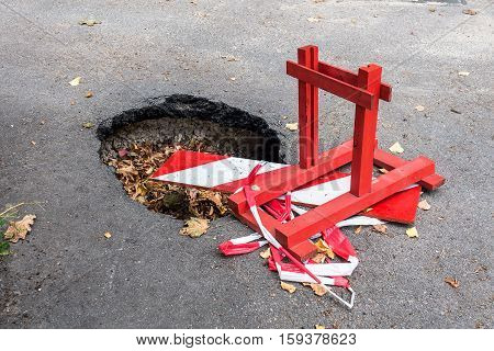 Big pothole on the road and warning sign. Road under constructon.