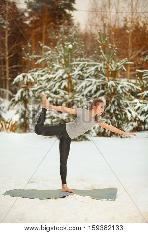 Beautiful Woman Doing Yoga Outdoors In Snow