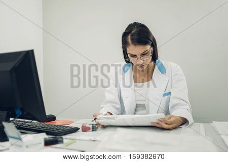 Taking care of your health concept. Young doctor prescribing medicines. Young general practicioner reading patients medical record