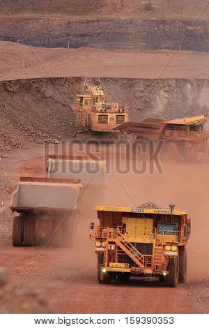 Fully loaded yellow XE-MC haul truck carrying waste rock at the Tom Price iron ore mine in the Pilbara region of Western Australia