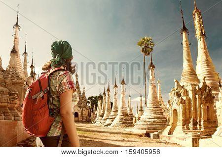 Backpacker traveling with backpack and looks at Buddhist stupas 
