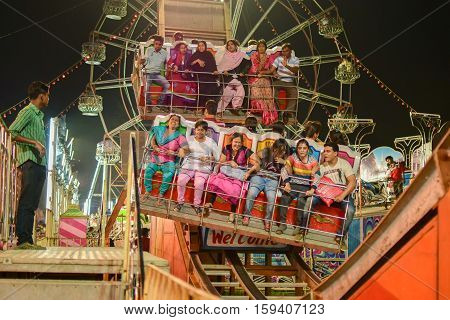 HOWRAH WEST BENGAL INDIA - MARCH 1ST MARCH 2015 : Young people enjoying Roller coster ride at Howrah West Bengal India. Shot at night with colored lights.