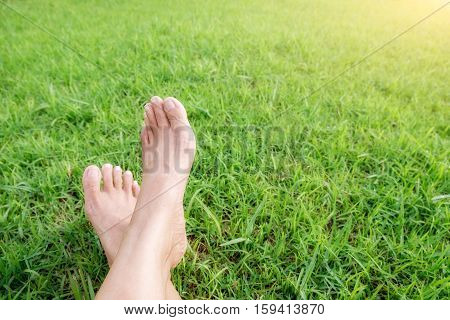 Feet of asian woman relaxing on a sofa and looking outside a green background view at home terrace. Relaxing concept.