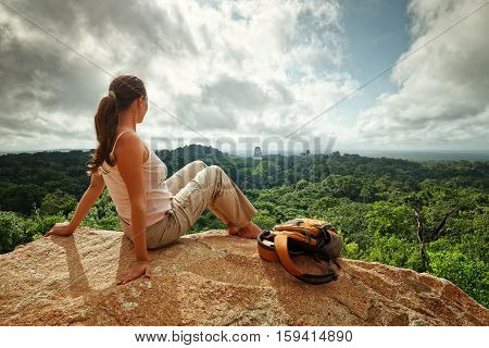 A young woman with a backpack is looking at the ruins of an ancient Maya city Tikal. Guatemala