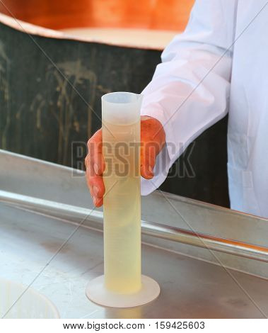 cheesemaker grab with the hand a plastic tube with the rennet to production of cheese on the farm