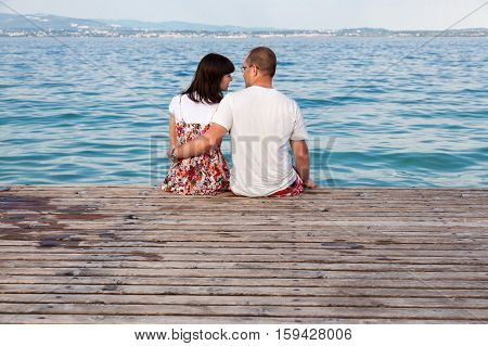 love couple sitting on a pier overlooking the sea