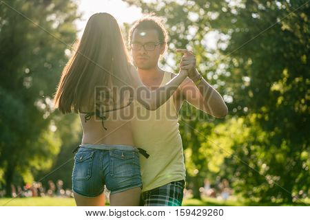 Mann turning woman while dancing Bachata in the sun