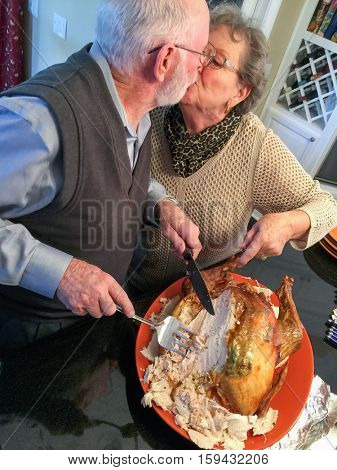 Senior Adult Couple Cutting the Holiday Turkey Together In The Kitchen.