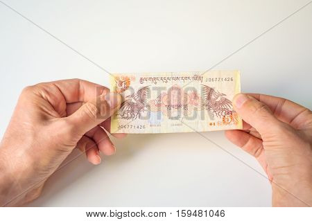 Man Holding Five Bhutanese Ngultrum Banknote In His Hands