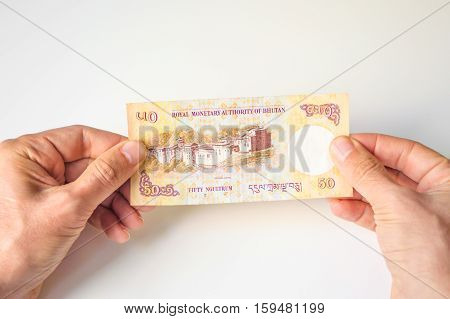 Man Holding Fifty Bhutanese Ngultrum Banknote In His Hands
