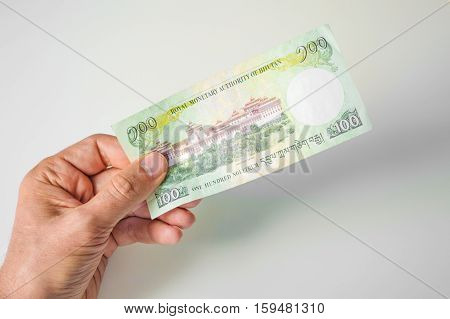 Man Holding Hundred Bhutanese Ngultrum Banknote In His Hand