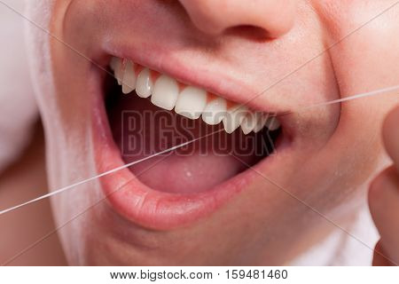 Young Man Cleaning Her White Teeth With Dental Floss