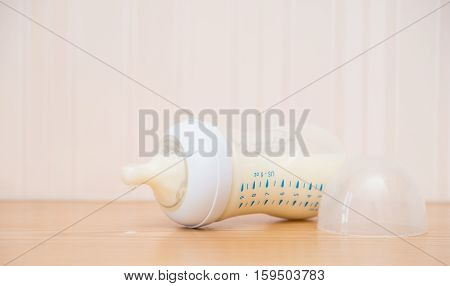 baby bottle and milk on a wood table close up