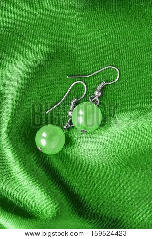 Nephrite earrings on green satin as a background