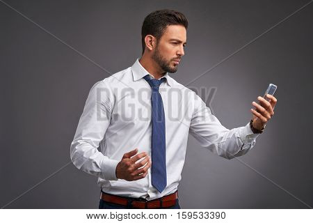 A handsome young man feeling upset while holding and looking at his smartphone